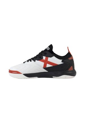Zapatilla deportiva de corte bajo con base de tela blanca, talón y cordones negros, acentos rojos y suela de goma, mostrada desde el lado izquierdo.