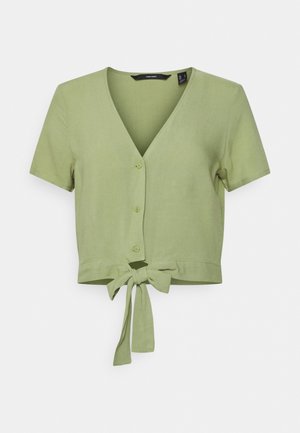 Blouse courte à manches courtes et col en V, de couleur vert clair, en tissu doux, avec une fermeture nouée à la taille et des détails de boutons sur le devant.