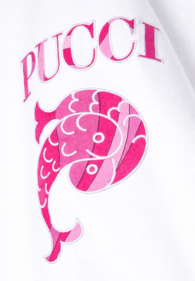 Tissu blanc avec un motif stylisé de poisson rose et le texte en majuscules rose "PUCCI" au-dessus du poisson sur un vêtement.