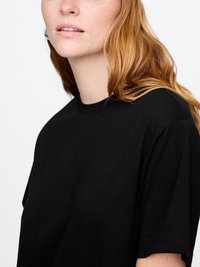 T-shirt en coton noir avec une coupe décontractée, col rond et manches courtes, présentant une texture douce et un design minimaliste.