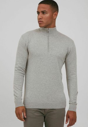 Suéter de cremallera color gris claro, hecho de material suave, con mangas largas, un cuello alto y puños y dobladillo acanalados para un ajuste ceñido.