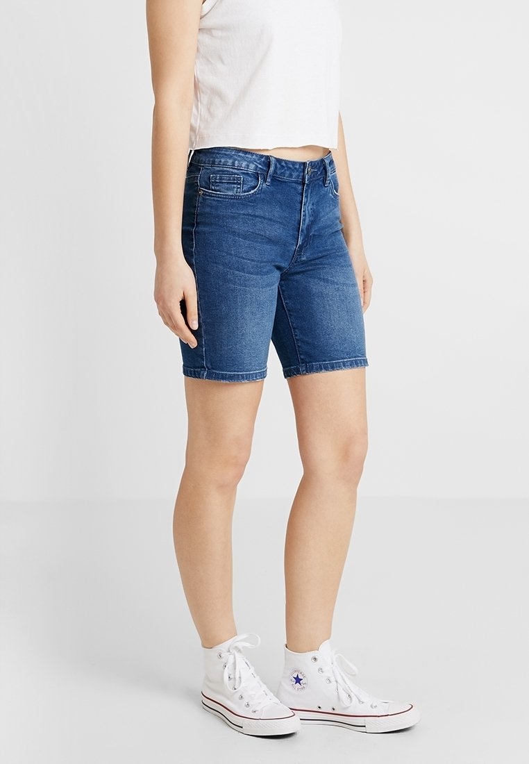 Džínové šortky v tmavě modré barvě s úzkým střihem a délce po kolena. Mají zapínání na knoflík a zip, pět kapes a prošitý lem.