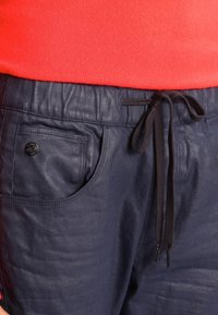 Námořnické lehké kalhoty vyrobené z hladké látky, s elastickým pasem, zatahovací šňůrkou a přední kapsou s černým knoflíkem.
