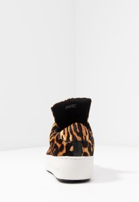Sneaker in stampa leopardata con una parte superiore morbida e testurizzata, colletto in tessuto nero e suola in gomma bianca. Design minimalista con un'estetica sportiva.