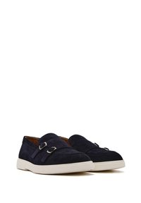 Scarpe slip-on in suede blu navy con suola piatta in gomma bianca, caratterizzate da fibbie decorative in argento e dettagli di cucitura sulla tomaia.