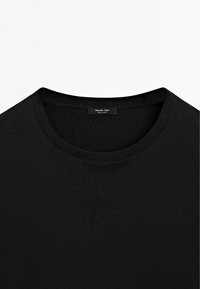 Schwarzes Baumwoll-T-Shirt mit Rundhalsausschnitt, das den Kragen und das Innenetikett mit dem Markennamen "Massimo Dutti" sowie dem Schriftzug "Made in China" zeigt.