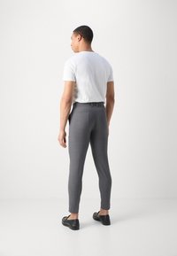 Gray tailored trousers with a slim fit, featuring a smooth texture, belt loops, and back pockets, paired with a plain white t-shirt.