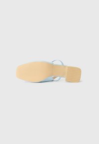Scarpa azzurra con un design elegante, caratterizzata da una parte superiore liscia, punta quadrata e una suola beige texturizzata. Le cinghie offrono ulteriore supporto.