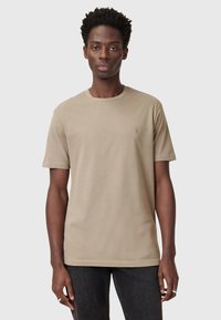 Beige cotton t-shirt with a crew neck and short sleeves, featuring a small embroidered logo on the chest. Classic fit, soft texture.