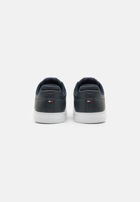 Sneakers in pelle blu scuro con suole in gomma bianche. Presentano un colletto imbottito, una linguetta testurizzata e un piccolo logo del marchio sul tallone.