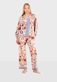 Floral-patterned two-piece pajama set in pink with blue and red accents. Features long sleeves and loose-fitting pants with a drawstring waist.
