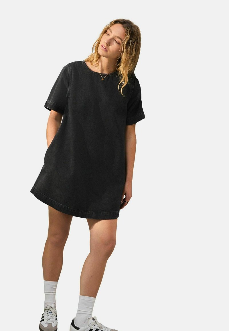 Schwarzes Denim-Kleid mit kurzen Ärmeln, rundem Halsausschnitt und legerem Schnitt. Es hat einen geraden Saum und dezente Nähakzente.