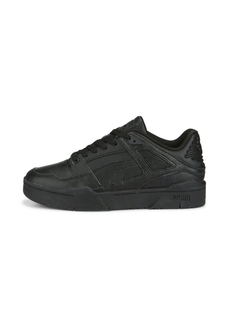 Sort low-top Puma sneakers i tekstureret læder, med snørebånd foran, polstret krave og tyk sål, vist i sideprofil på hvid baggrund.