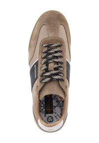 Beige suède sneaker met zwarte leren accenten, gemusterde veters en een gevoerde binnenzijde. Heeft een rubberen zool en logo-detail op de zijkant.
