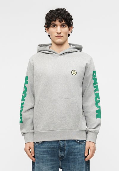 Young man with curly black hair wearing a gray hoodie with green "BARKOW" text on sleeves and a small yellow smiley face logo on chest.