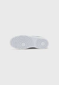 Semelle en caoutchouc blanche avec des motifs circulaires, surface texturée et rainures prononcées. Présente une forme incurvée élégante et un rembourrage épais.