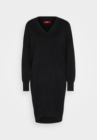 Robe noire en maille à manches longues avec col en V, poignets côtelés et ourlet arrière légèrement plus long.