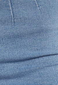 Blå denimtyg med en slät textur och lätt stretch, med en subtil diagonal väv och minimala sömnadsdetaljer.