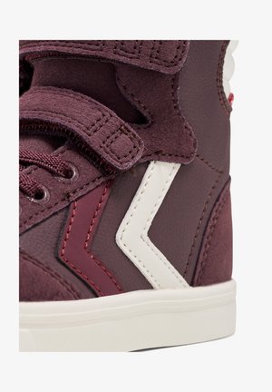 Sneaker alta color bordeaux in suede strutturato e pelle liscia. Caratterizzata da un design a zigzag bianco, chiusura con lacci e fasce in velcro, e suola in gomma.