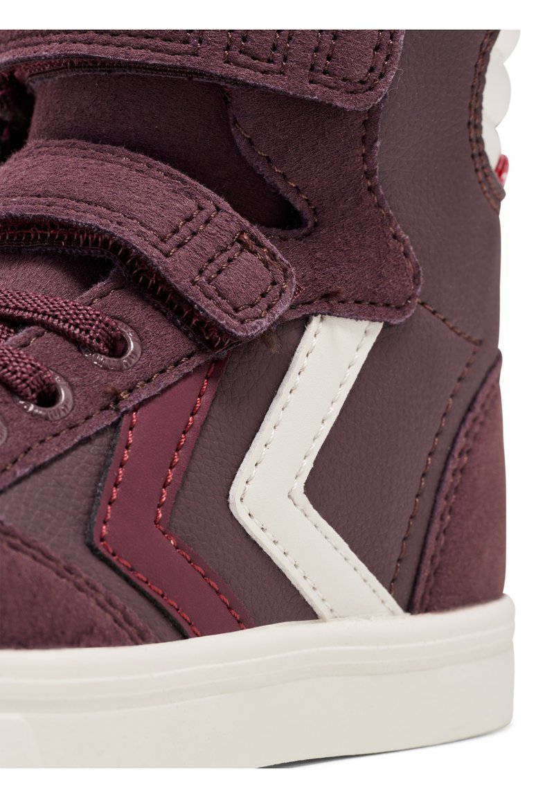 Bordeauxfarbene High-Top-Sneaker aus strukturiertem Wildleder und glattem Leder. Merkmale sind ein weißes Zickzackdesign, Schnürung und Klettverschlüsse sowie eine Gummisohle.