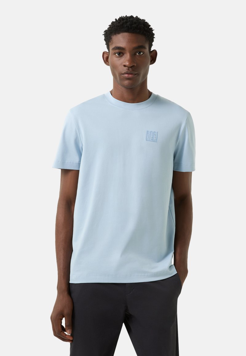 Světlomodré tričko s krátkým rukávem z měkké bavlny s malým logem na hrudi. Pohodlný střih s kulatým výstřihem a hladkou texturou.