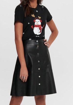 Sort t-shirt med et sne-mand grafik, der har hjerter og snefnug; parret med en knælængde sort faux lædernederdel med knapper.