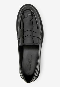 Mocasines de charol negro con una correa ancha y acentos de costura, que presentan una superficie lisa y un diseño de puntera redonda.