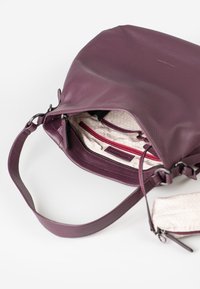 Purple leather handbag with an exterior zip closure, textured surface, and an inner patterned lining. Includes red zippered pocket detail.