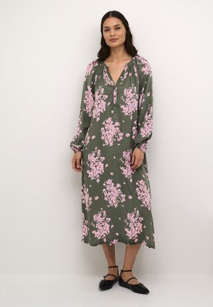 Robe longue à manches longues, vert olive, ornée de motifs floraux roses, avec décolleté en V et manches froncées, tombant mi-mollet avec une coupe ample.
