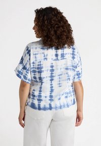 Blusa a maniche corte in tie-dye blu e bianco con vestibilità ampia, orlo leggermente curvo e dettaglio nella parte posteriore. Tessuto morbido e leggero.