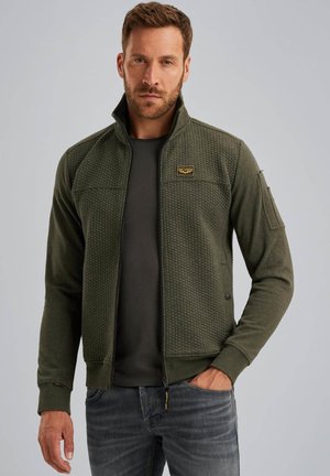 Green zip-up jacket with textured front, smooth sleeves, and a high collar. Features logo patch on chest and side pocket with zip.