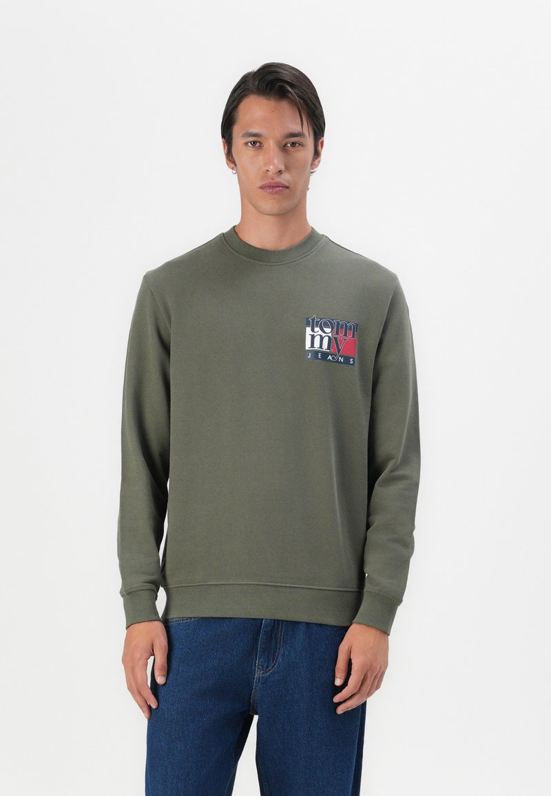 Olivenfarvet sweatshirt med lange ærmer, rund halsudskæring og et lille trykt logo i rød, hvid og blå på brystet.