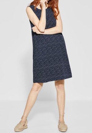 Robe sans manches bleu marine avec un motif floral, coupe décontractée, longueur genou, associée à des espadrilles beige clair. Tissu léger.