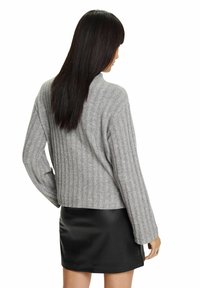 Harmaa ribbipaita rentoa istuvuutta, pitkät hihat ja lyhyt helma, yhdistettynä mustaan nahkaminihameeseen.