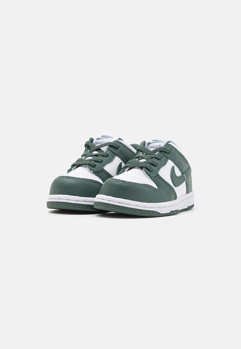 Zapatillas verdes y blancas con parte superior de cuero, puntera perforada y suela de goma. Presentan cordones y el logo de Nike en el lateral.