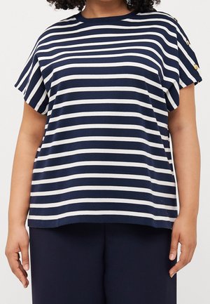Personne portant un haut à manches courtes rayé horizontal bleu marine et blanc avec des boutons dorés sur l'épaule et un pantalon bleu marine foncé.