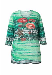 Zielona tunika w paski z czerwonymi ustami i napisem "KISS" oraz gwiazdą w zwierzęcy wzór. Miękki materiał o luźnym kroju.