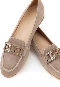 Mocasines de ante beige con un acento de metal dorado y un ribete de color crema. Diseño de punta redonda y suela plana, con una textura suave.