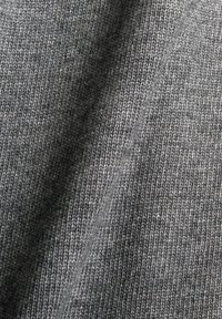 Tissu tricoté gris avec une texture lisse, présentant un gros plan de points fins et uniformément espacés ainsi qu'un motif chiné subtil.