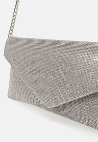 Petit sac pochette de soirée argenté recouvert de strass étincelants avec un rabat triangulaire et une bandoulière chaîne argentée.