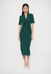 Zelené priliehavé midi šaty s krátkymi rukávmi, zapínaním na gombíky vpredu a záševkami v páse. Hladký, elastický materiál.