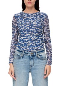 Langsleeve top in blauw met een abstract crèmekleurig patroon, gemaakt van een lichtgewicht, doorschijnende stof. Gecombineerd met lichtgewassen denim jeans.