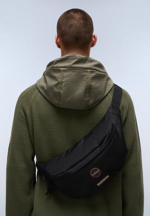 Schwarze Umhängetasche aus strapazierfähigem Gewebe, mit einer glatten Oberfläche, verstellbarem Riemen und einem runden Logo-Patch auf der Vorderseite.