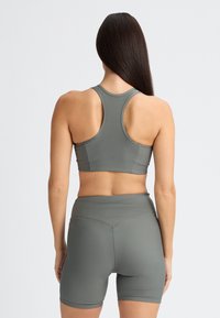 Ribbad grå idrottsbehå med racerback-design, tillsammans med högmidjade ribbade shorts, båda tillverkade av stretchigt material.