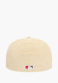 Gorra beige claro hecha de pana con una textura suave, con un pequeño parche con el logo de MLB en la parte delantera. Forma redondeada y sin cierre visible.