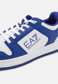 Blue and white sneaker made of leather and synthetic materials, featuring laces, a logo, and a textured rubber sole for traction.
