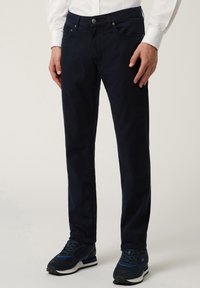 Pantaloni blu navy in cotone. Design dritto con due tasche frontali, una tasca per le monete e una tasca sul retro. Completati con un bottone di chiusura.