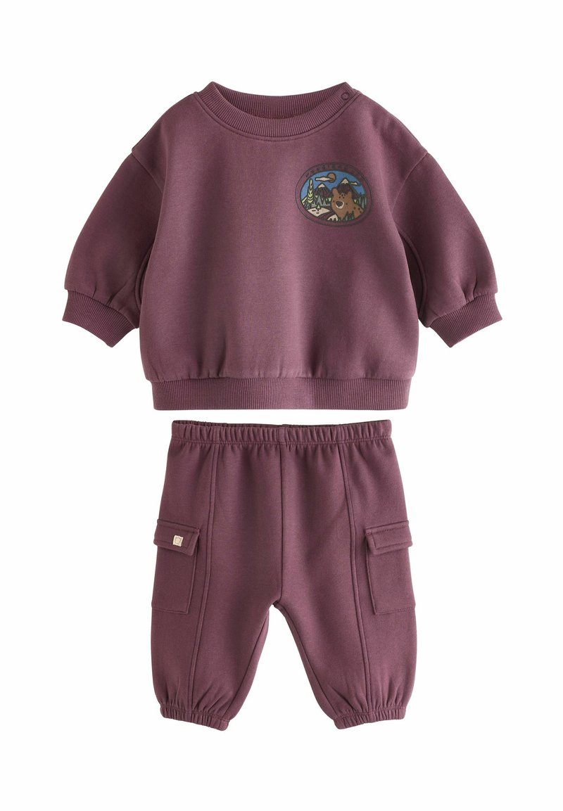 To-delt børnetøj i afdæmpet lilla, bestående af en t-shirt med korte ærmer og et rundt mærke samt joggerbukser med cargo-lommer.