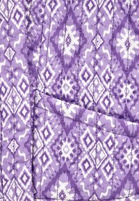 Lila kviltad tyg med ett geometriskt mönster i vitt. Designen inkluderar diamanter och virvlar med en texturerad yta.