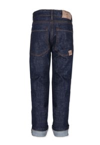 Tummansiniset farkut suoralla leikkauksella, joissa on käännetyt lahkeet, oranssit ompeleet ja ruskea nahkalaatta takana.